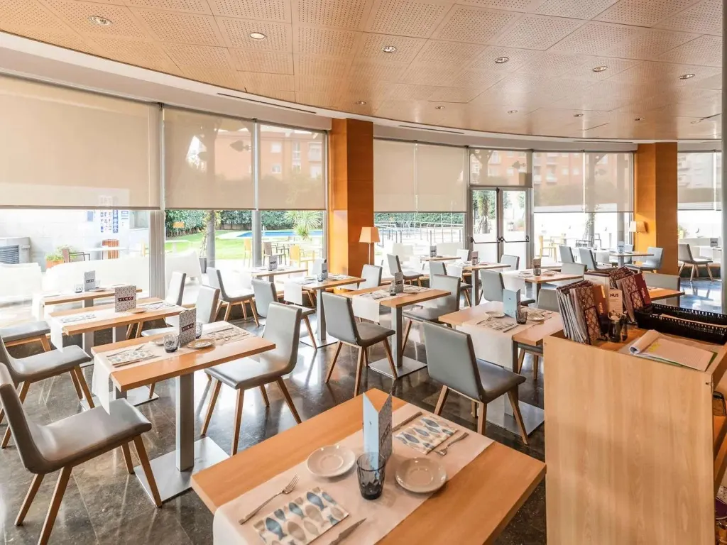Une salle lumineuse avec des tables dressées pour le repas.