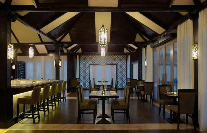 Une salle lumineuse avec un bar et des tables de restaurant.