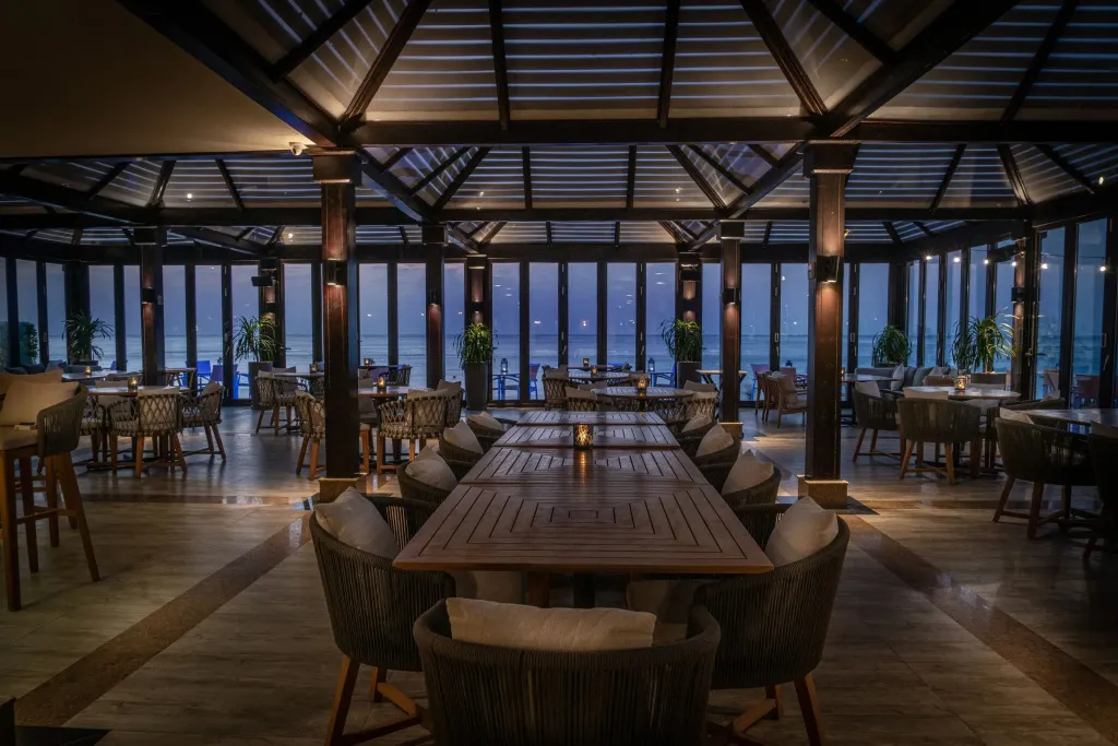 Une salle à manger lumineuse offre une vue sur la mer au crépuscule.