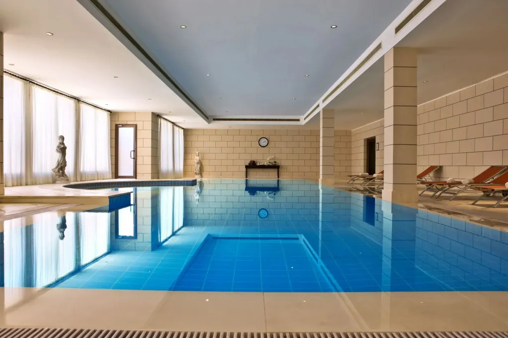 Une piscine intérieure rectangulaire avec des transats sur le côté.