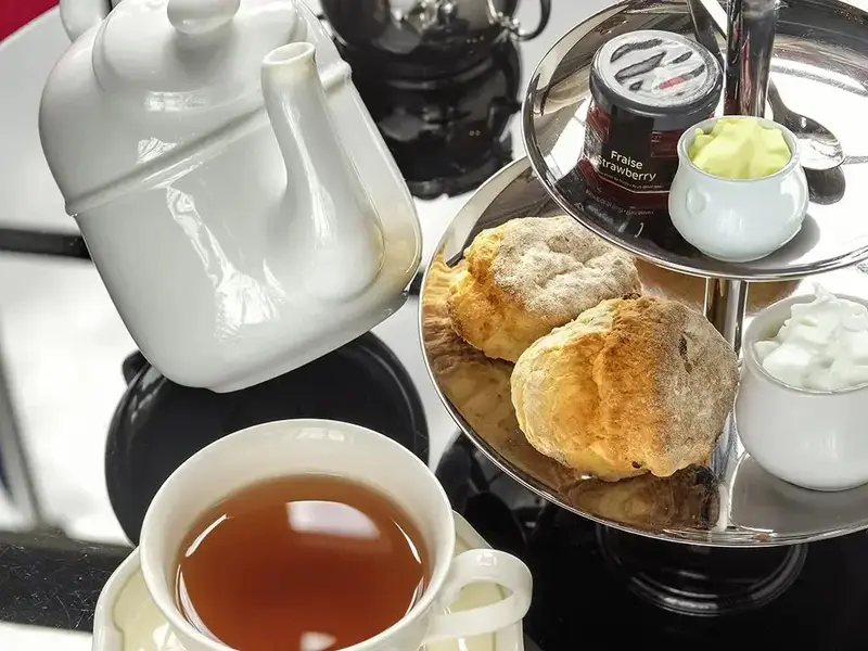 Une théière blanche et une sélection de pâtisseries sont présentées sur une table.