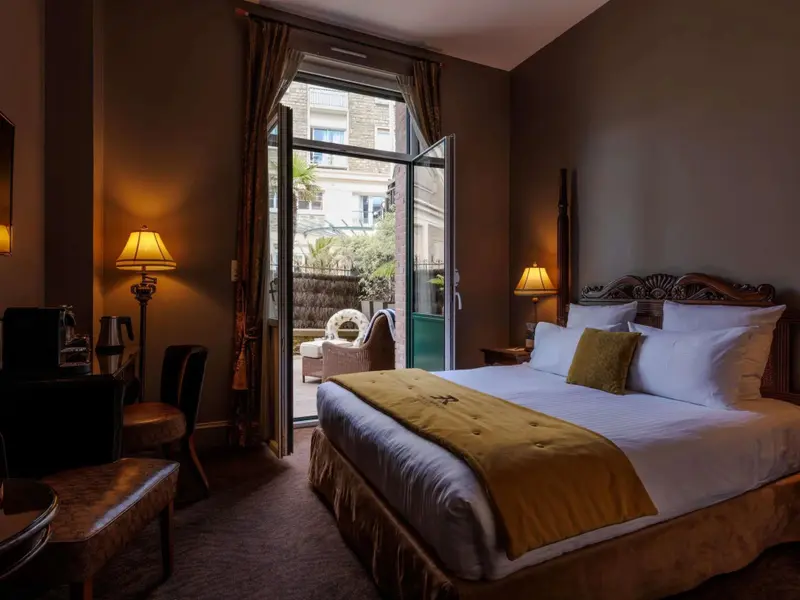 Une chambre lumineuse s'ouvre sur une terrasse fleurie.