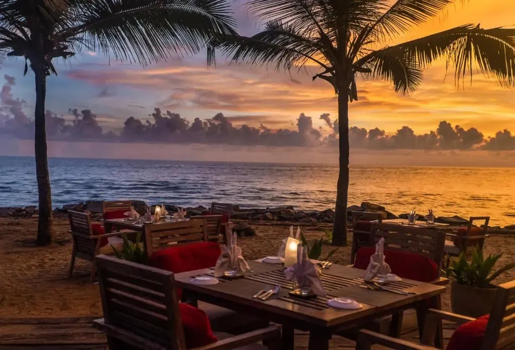 Tables dressées sur une plage au coucher du soleil.
