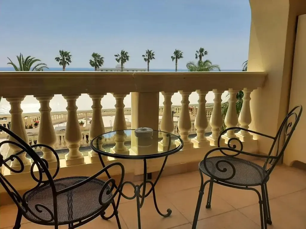 Une terrasse avec une table et des chaises offre une vue sur la mer et la plage.