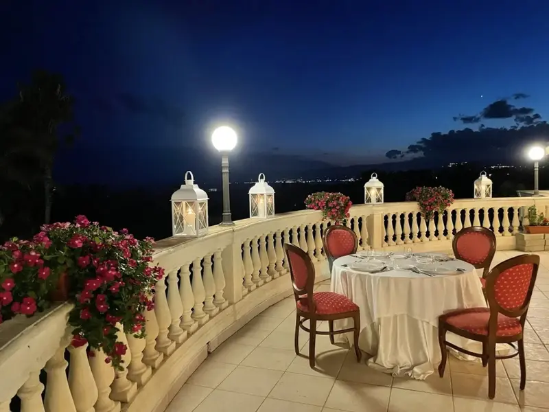 Table dressée sur une terrasse avec vue sur un paysage urbain illuminé.