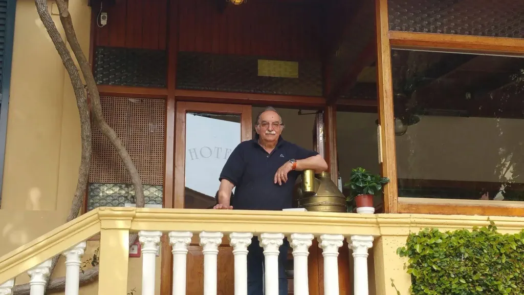 Un homme se tient sur un balcon orné de balustrades blanches.