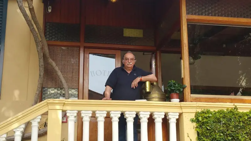 Un homme se tient sur un balcon orné de balustrades blanches.