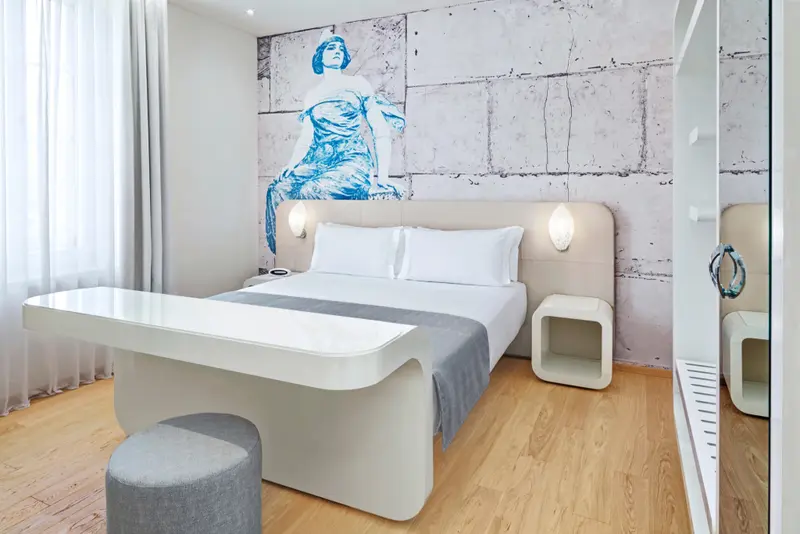 Une chambre lumineuse avec un grand lit et une décoration murale moderne.