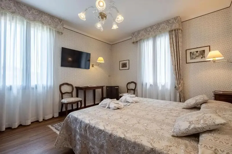 Une chambre lumineuse avec un grand lit et des meubles classiques.