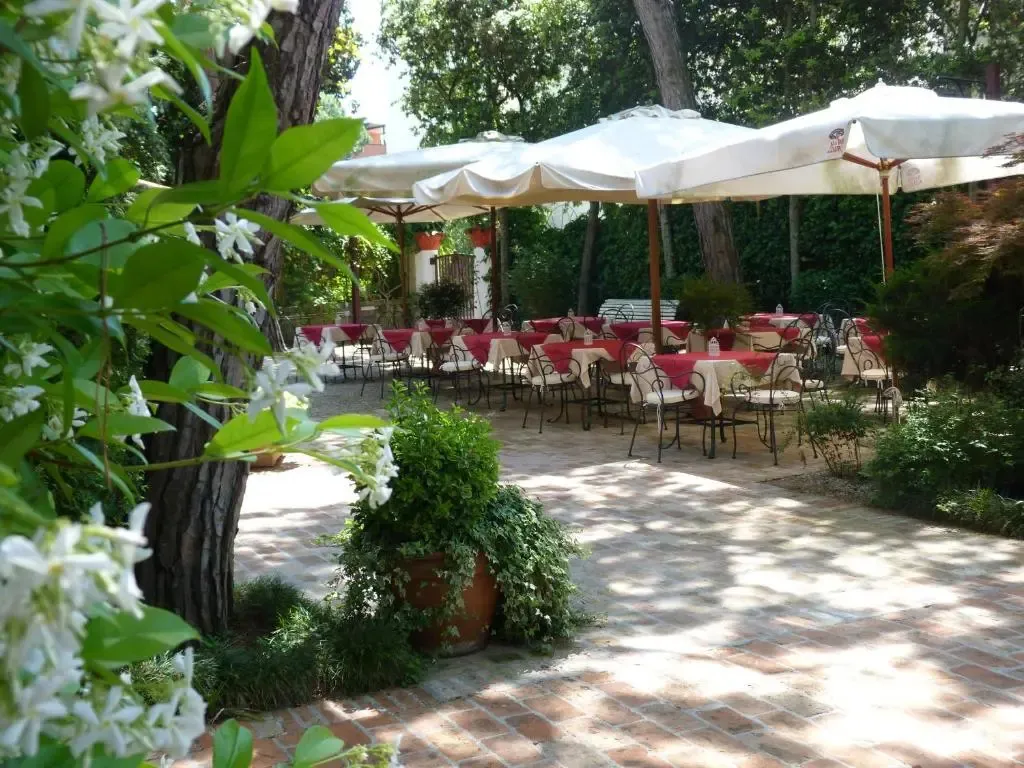 Une terrasse ombragée avec des tables dressées pour un repas en extérieur.