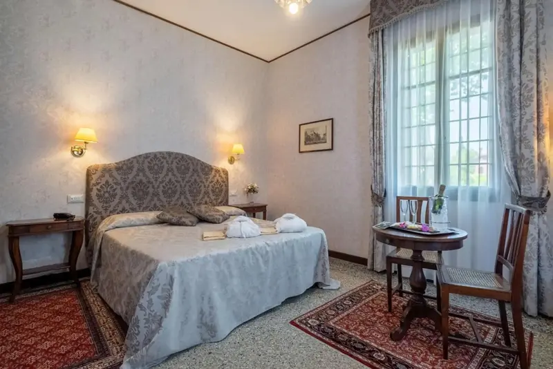 Une chambre lumineuse avec un grand lit et une table ronde près de la fenêtre.