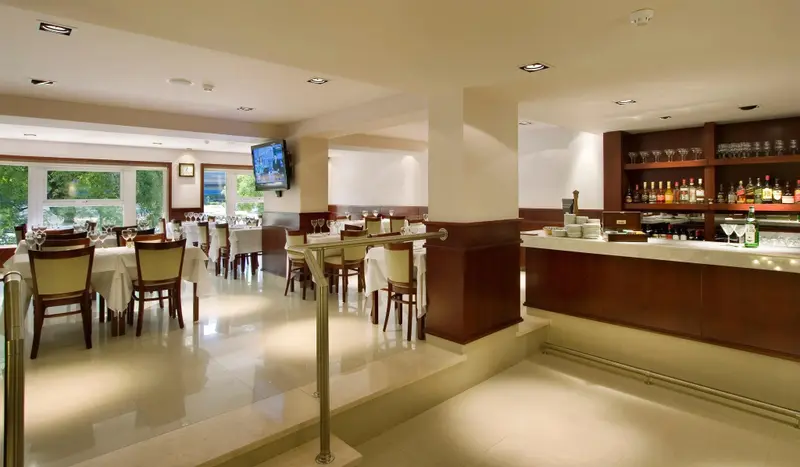 Une salle lumineuse avec des tables nappées et un comptoir de bar en bois.