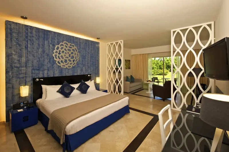 Une chambre lumineuse avec un grand lit et un espace salon.