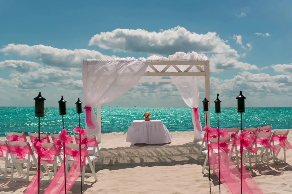 Une cérémonie de mariage est mise en place sur une plage de sable blanc face à la mer turquoise.