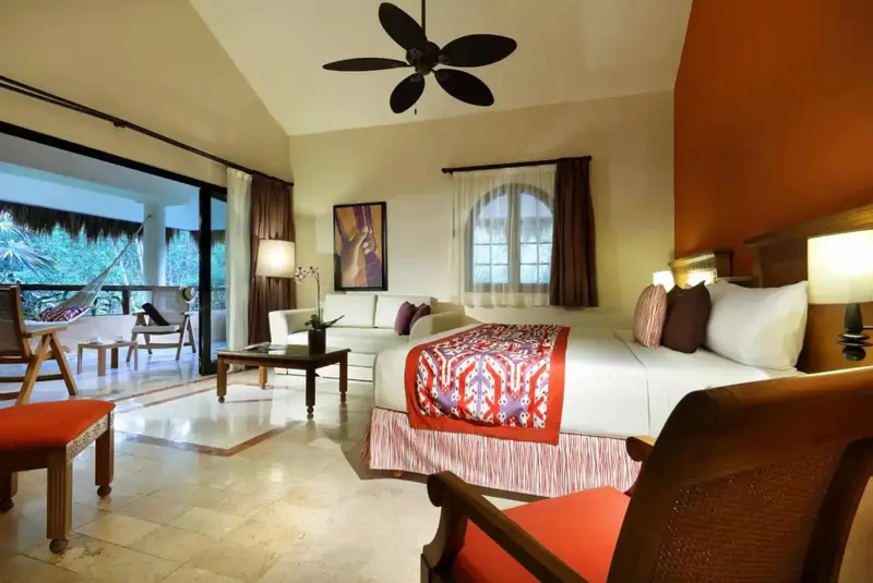 Une chambre lumineuse avec un lit king-size et un coin salon donnant sur une terrasse.