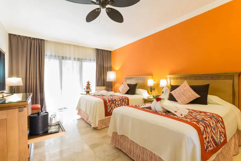 Chambre lumineuse avec deux lits décorés de serviettes en forme de cygnes.