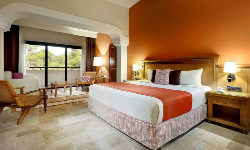 Une chambre lumineuse avec un grand lit et un coin salon.