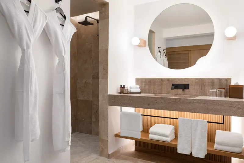 Une salle de bain moderne avec une douche à l'italienne et un grand miroir rond.