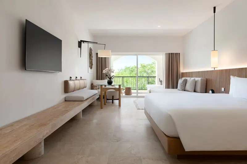 Une chambre lumineuse avec un grand lit et un espace salon.
