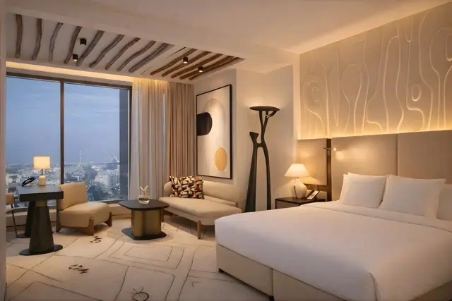 Une chambre lumineuse avec un lit et un espace salon près d'une grande fenêtre.