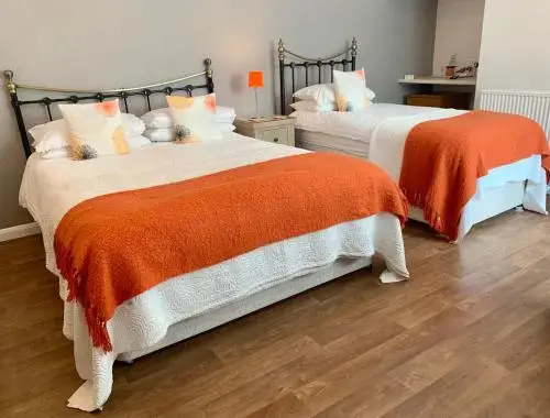 Deux lits simples avec couvertures orange dans une chambre lumineuse.