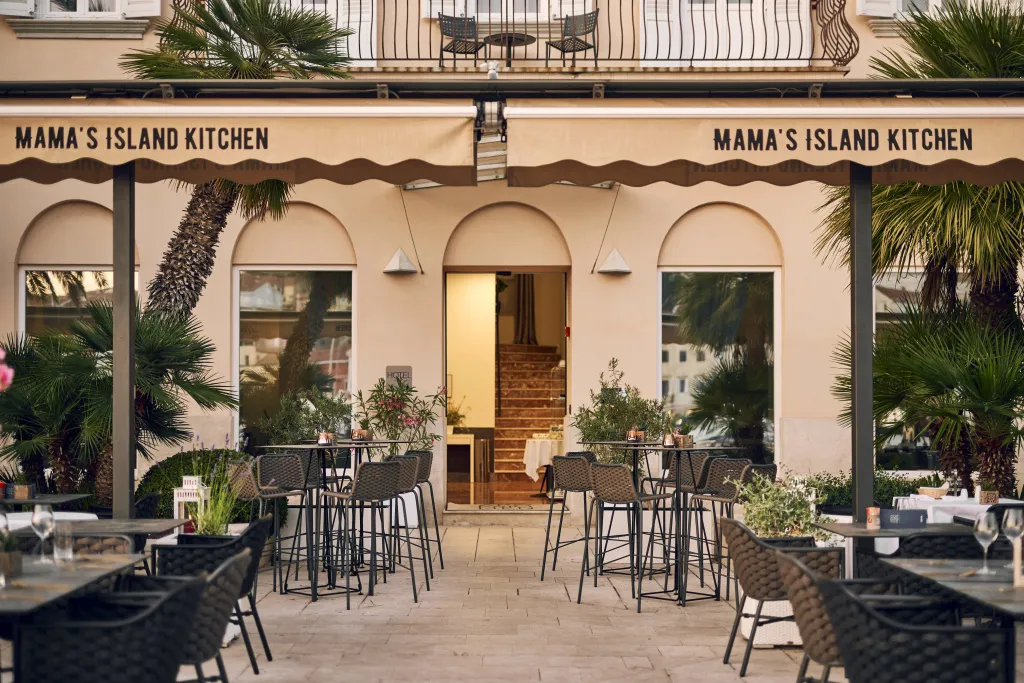 Terrasse ombragée avec tables et chaises devant un restaurant.