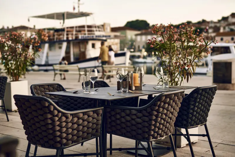 Une table est dressée sur une terrasse avec vue sur un port de plaisance.
