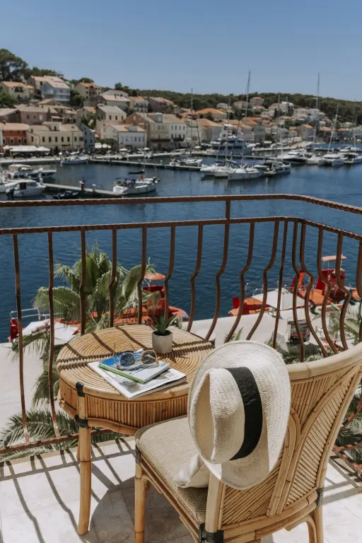 Une terrasse ensoleillée offre une vue sur un port de plaisance et une ville côtière.