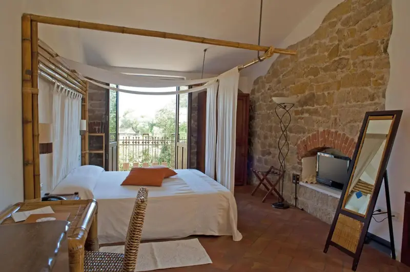 Une chambre lumineuse avec un lit à baldaquin et un accès à un balcon.