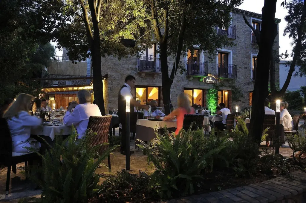 Une terrasse illuminée accueille des convives autour de tables nappées.