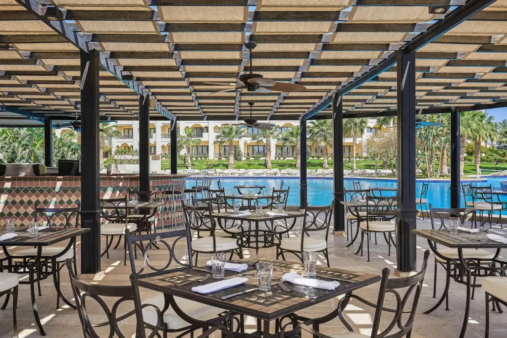Une terrasse ombragée avec des tables et des chaises près d'une piscine.