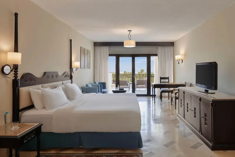 Une chambre lumineuse avec un grand lit et un accès à un balcon.