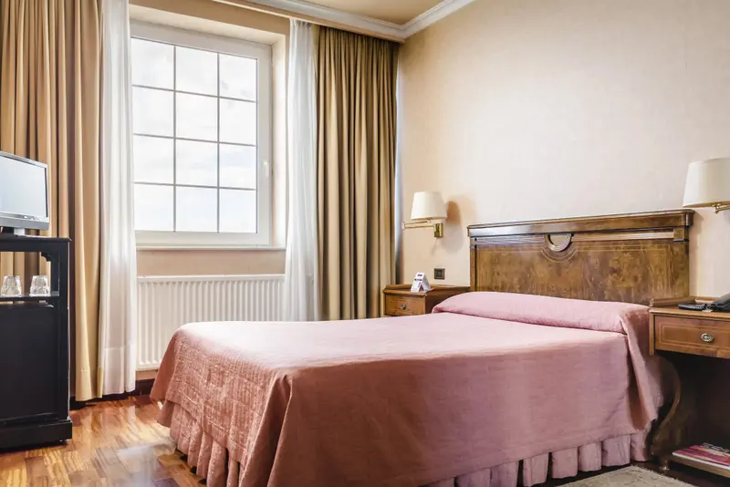 Une chambre à coucher lumineuse avec un lit recouvert d'une courtepointe rose et des meubles en bois.