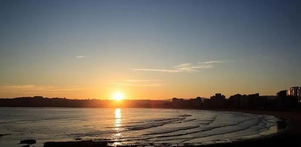 Coucher de soleil sur une plage avec des bâtiments en arrière-plan.
