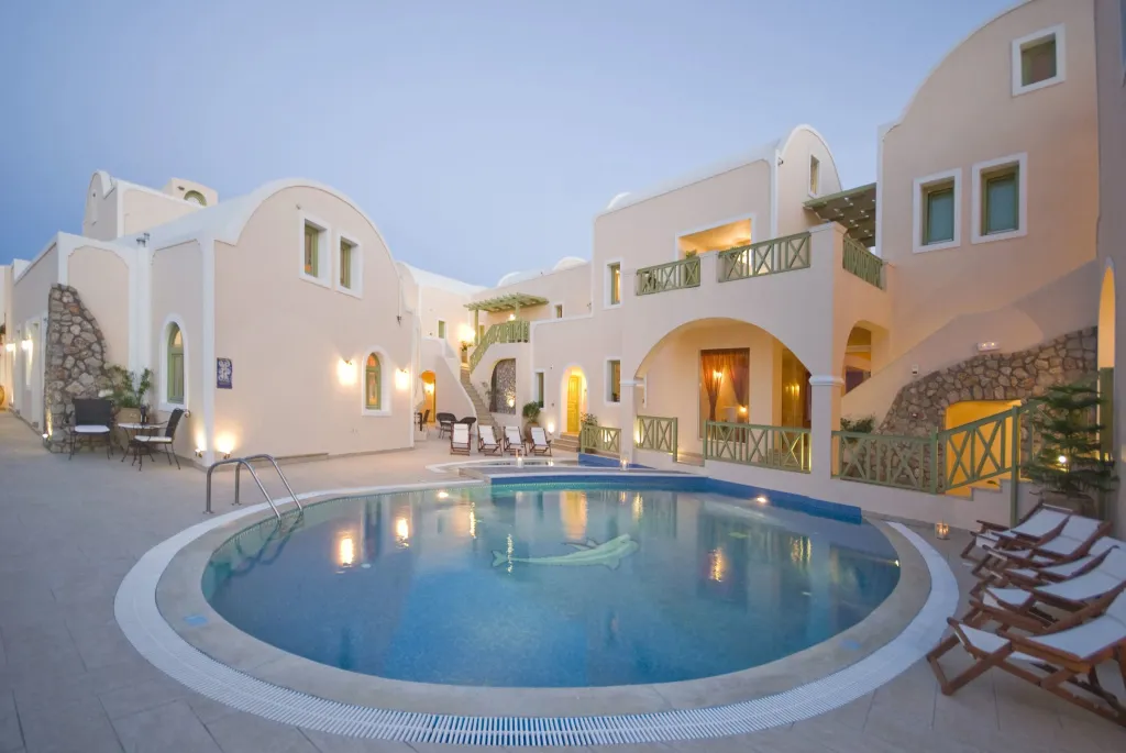Bâtiment blanc avec piscine et transats sous un ciel bleu.