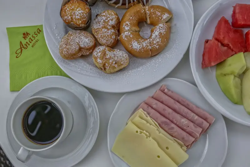 Assiette de viennoiseries, de fruits et de charcuterie accompagnant une tasse de café.