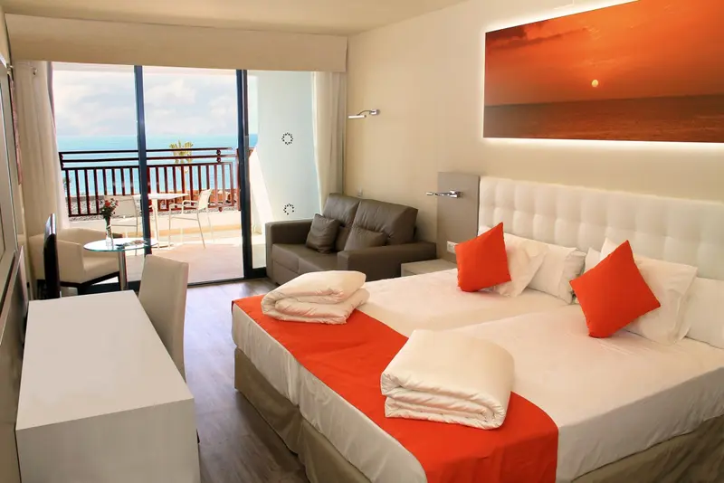 Une chambre lumineuse avec un grand lit et un accès à un balcon.