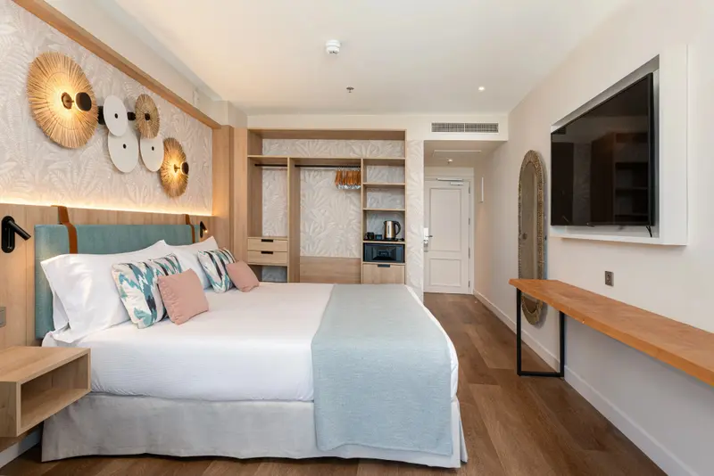 Une chambre lumineuse avec un grand lit et une décoration murale en fibres naturelles.