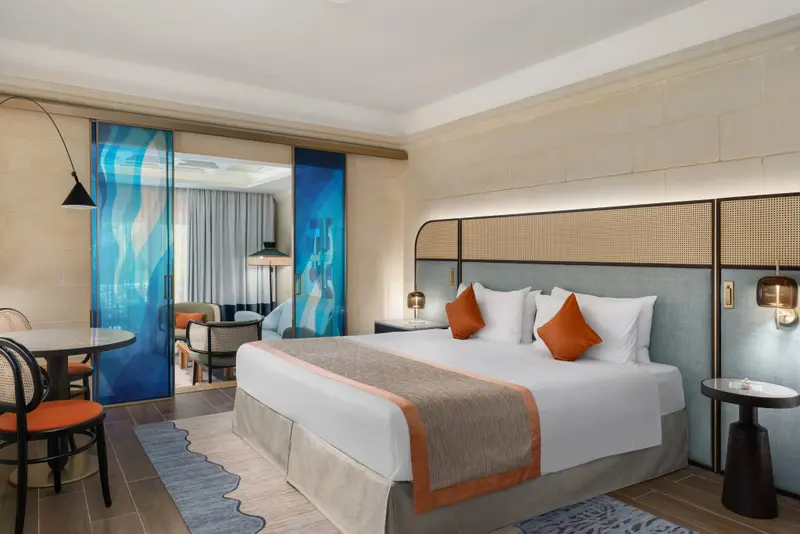 Une chambre lumineuse avec un grand lit et un coin repas.