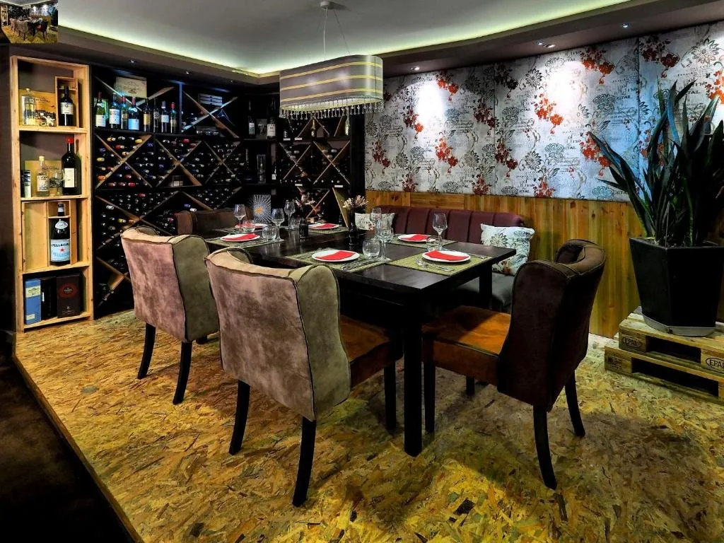 Une table dressée dans une salle à manger décorée de bouteilles de vin et de motifs floraux.