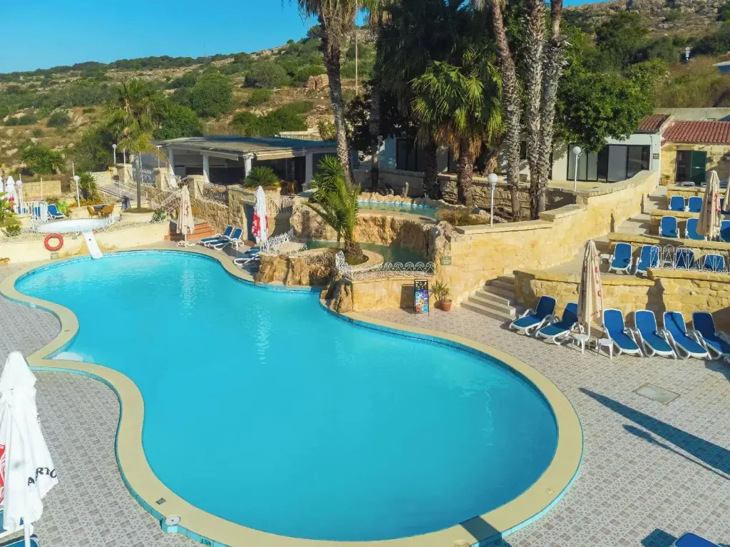 Piscine extérieure avec transats et végétation luxuriante.