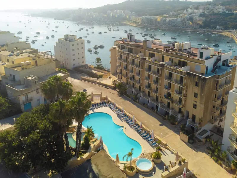 Vue aérienne d'un bâtiment beige avec une piscine et des transats.