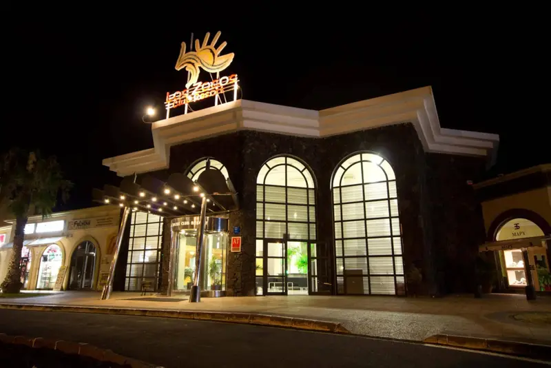 Façade d'un bâtiment illuminé la nuit avec une enseigne lumineuse.