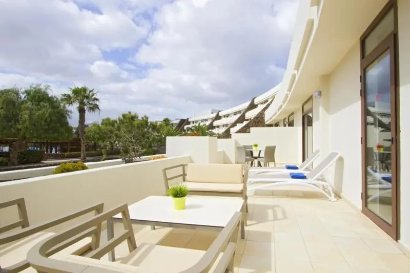 Terrasse aménagée avec salon et transats face à un paysage verdoyant.