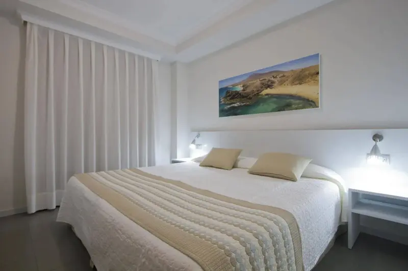 Une chambre lumineuse avec un grand lit et des rideaux blancs.