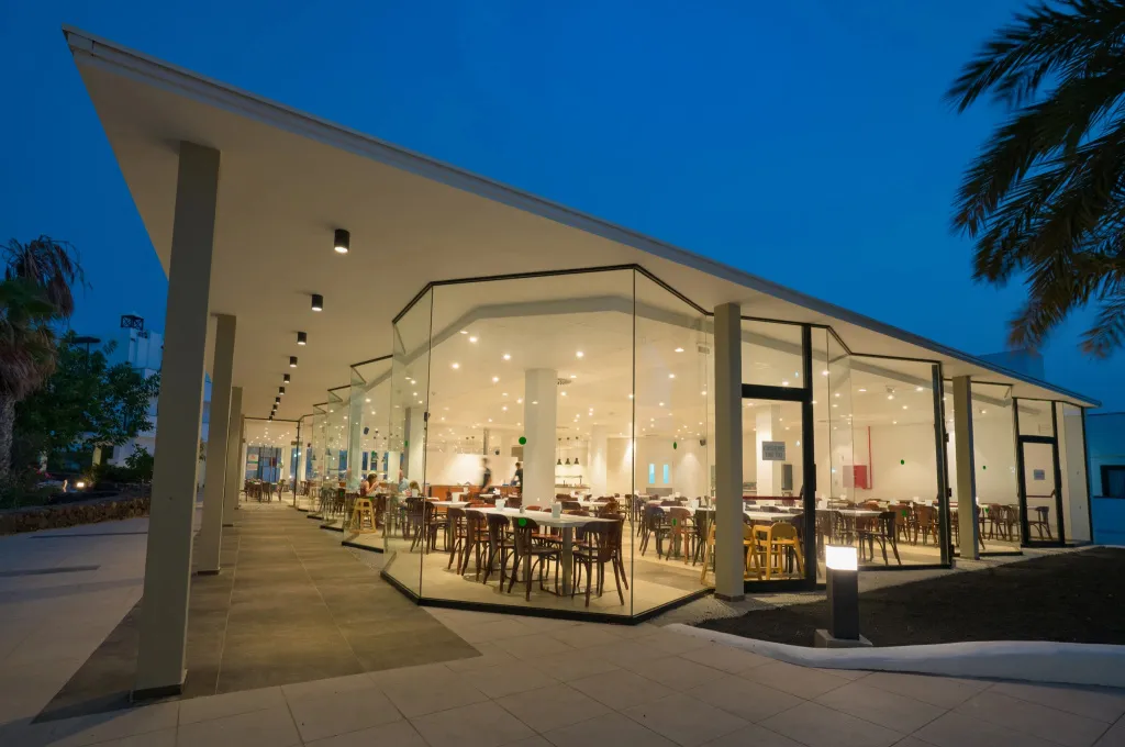 Une salle lumineuse avec de grandes baies vitrées et des tables disposées à l'intérieur.