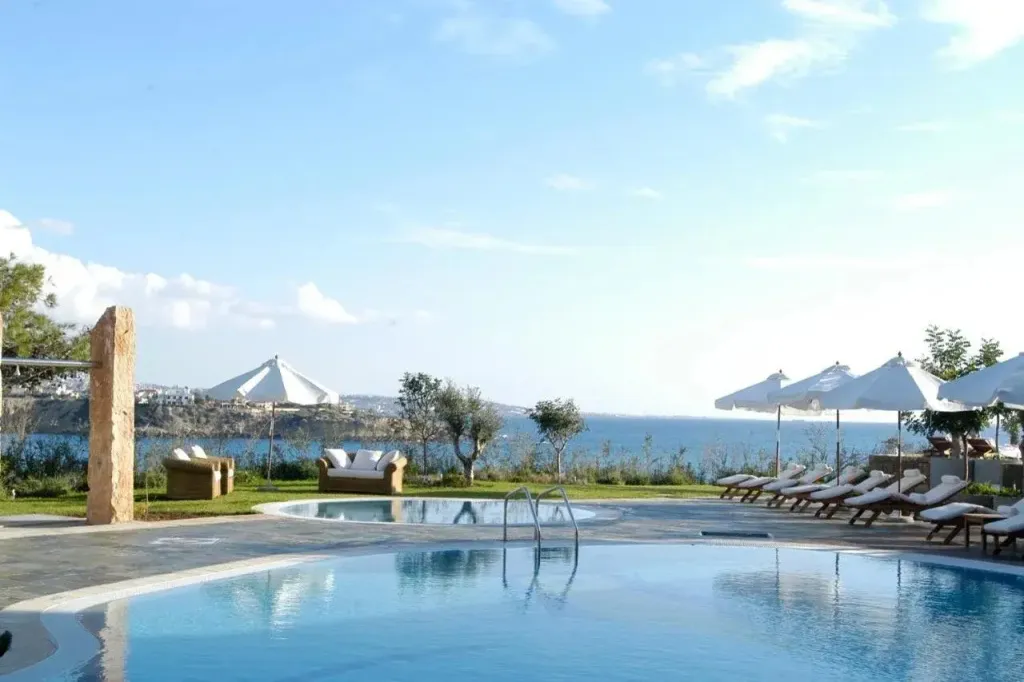 Piscine d'hôtel avec transats et vue sur la mer.