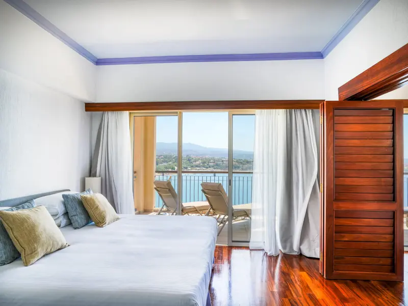 Une chambre lumineuse s'ouvre sur une terrasse avec vue sur la mer.