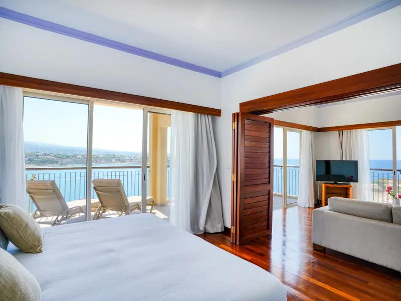 Une chambre lumineuse s'ouvre sur une terrasse avec vue sur la mer.
