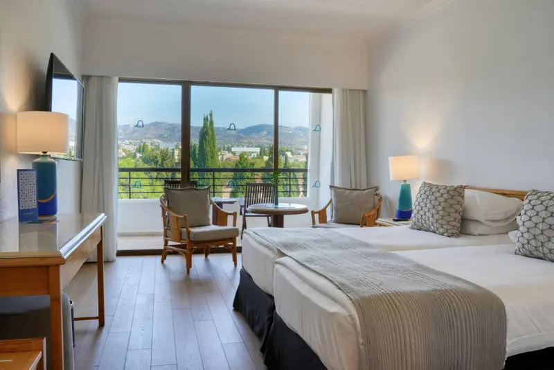 Chambre lumineuse avec vue sur un paysage montagneux.